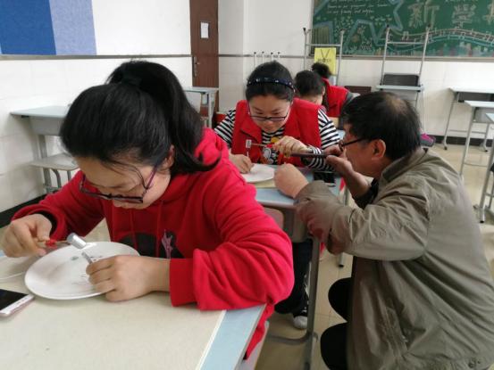 0106_101240_582.jpg 程佩初正在指导青少年学生学习刻瓷技巧.jpg